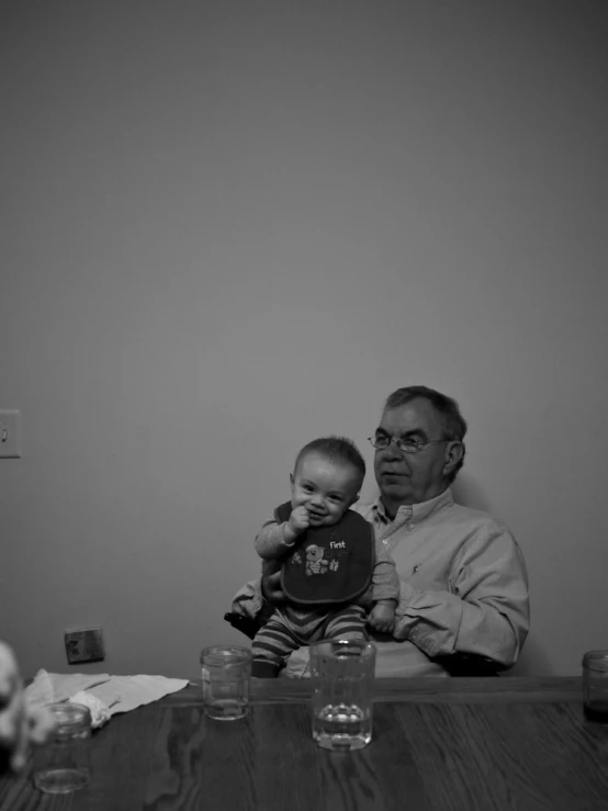 an old man holding a baby on a table