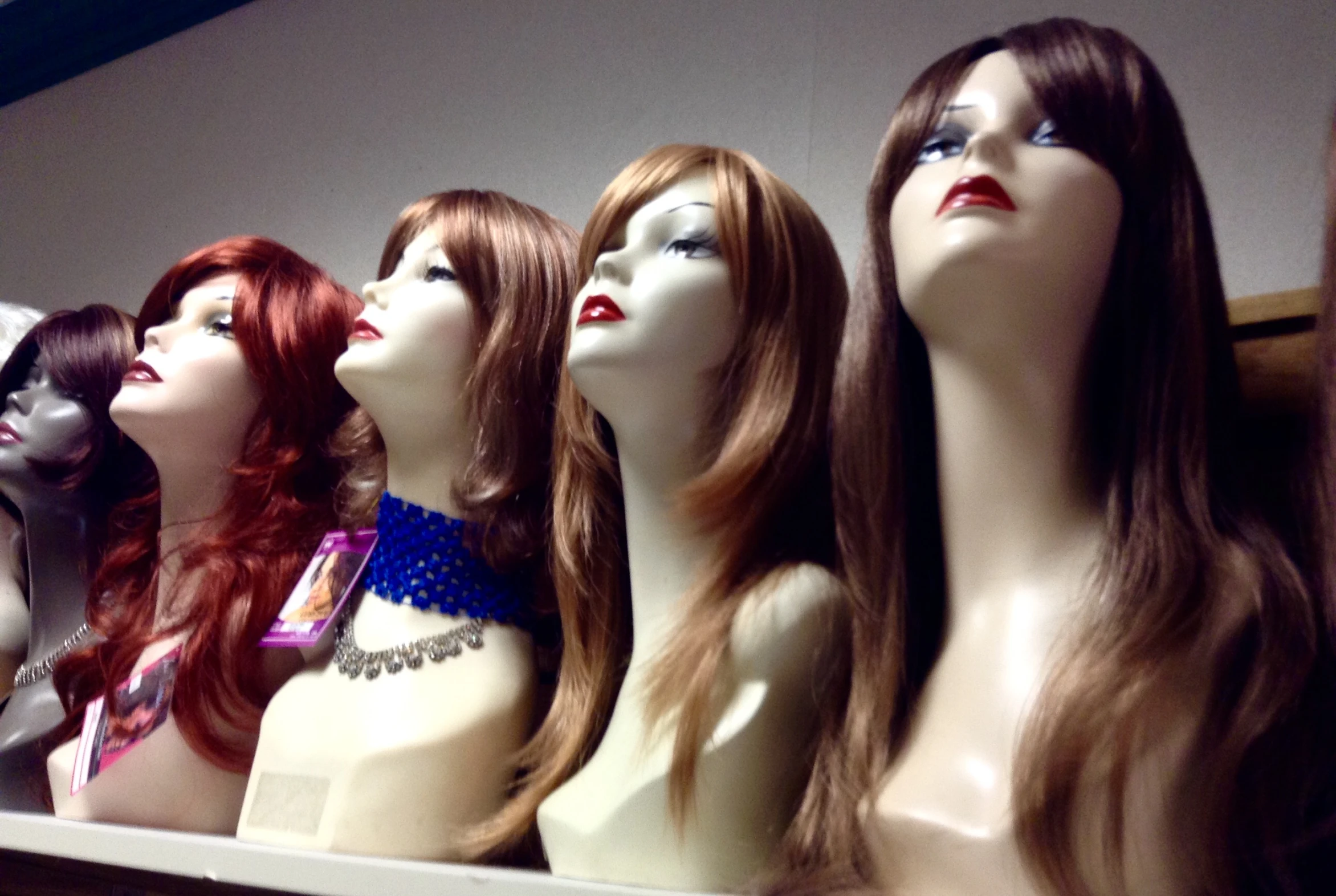 a large display of female mannequin heads on shelves