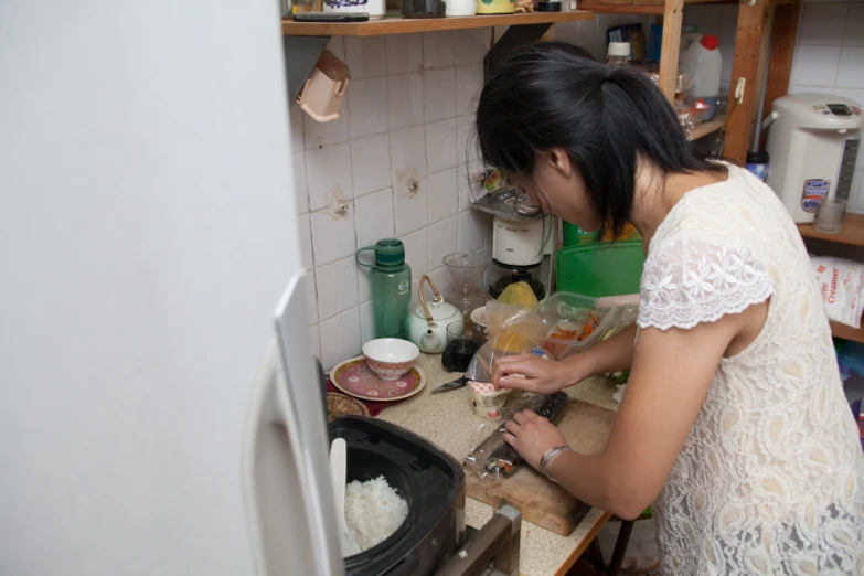 a woman in a kitchen making food using a slicer