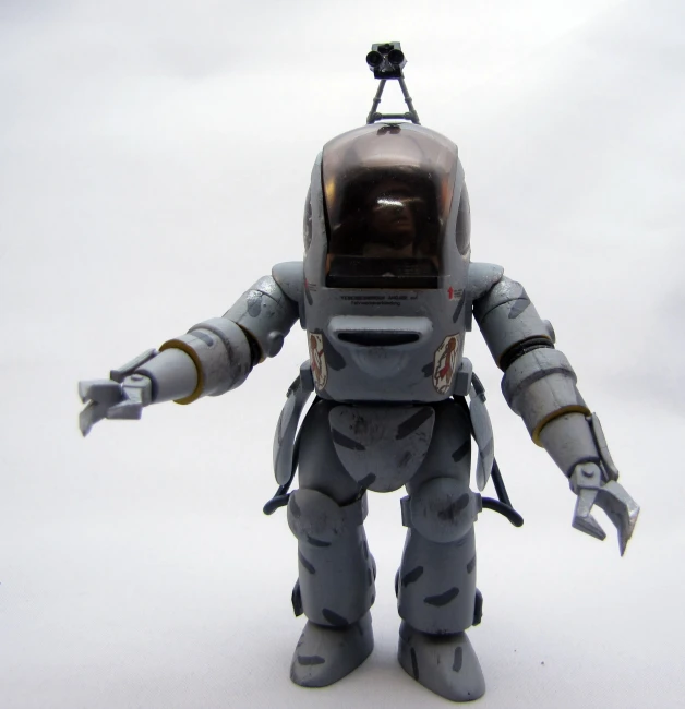 an antique toy model of a grey robot standing