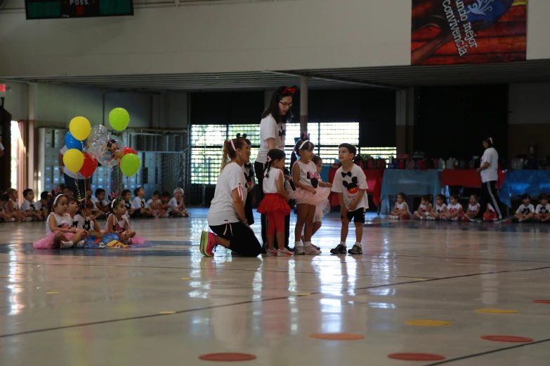 two girls are handing off balloons at a sports event