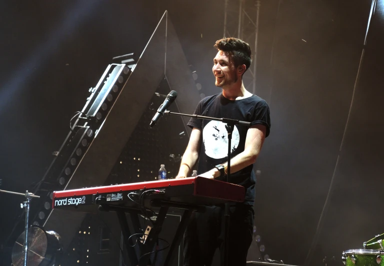 a man playing a keyboard in front of some microphones