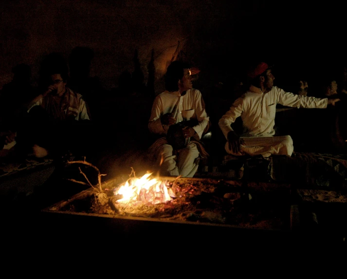 men are sitting around a table in the dark