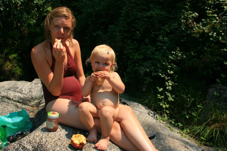 two women sitting on top of a large rock