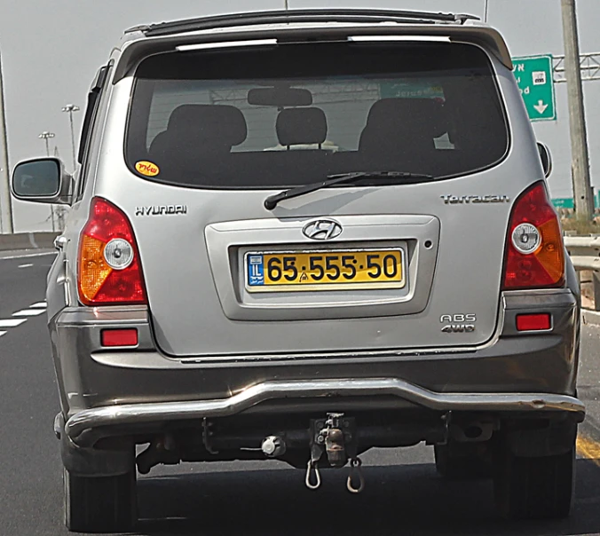 rear view of silver toyota muv from behind with car number plate on road