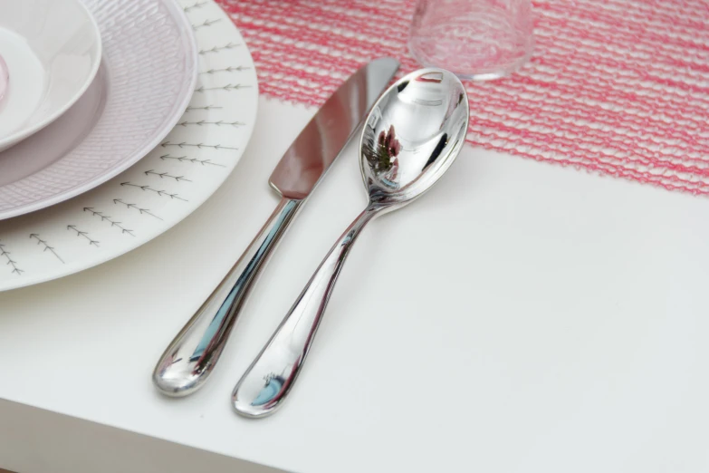 a table setting with plates and silverware and a pink place mat