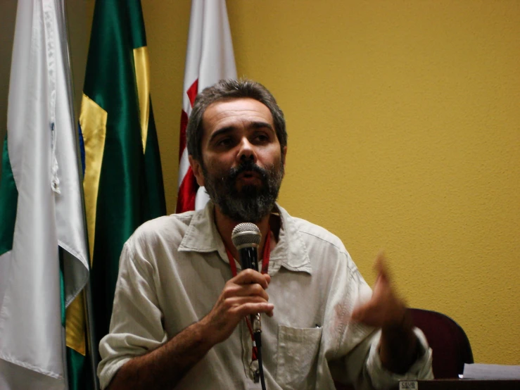 a man is talking into a microphone in front of flags
