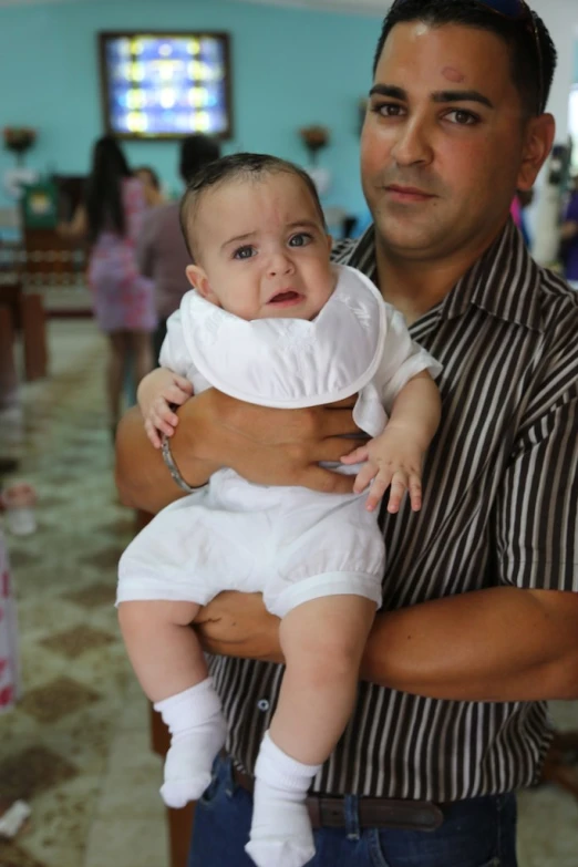 the man holds up the baby wearing a costume