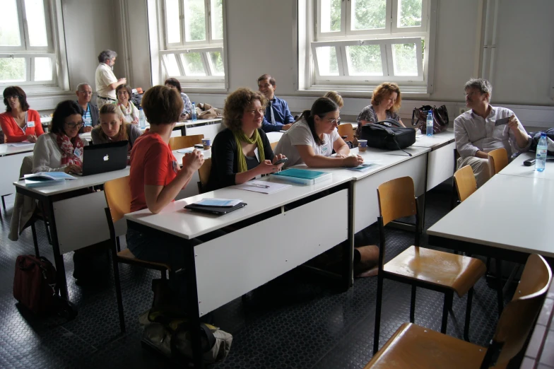 group of people sitting in desks at white and black desks