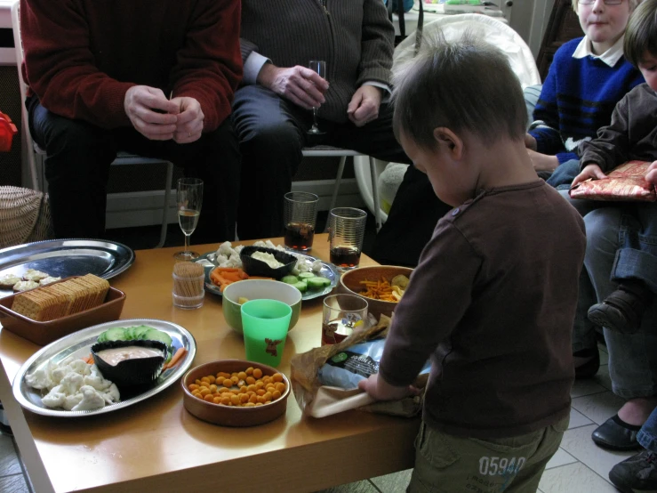 a little boy standing by a table with food on it