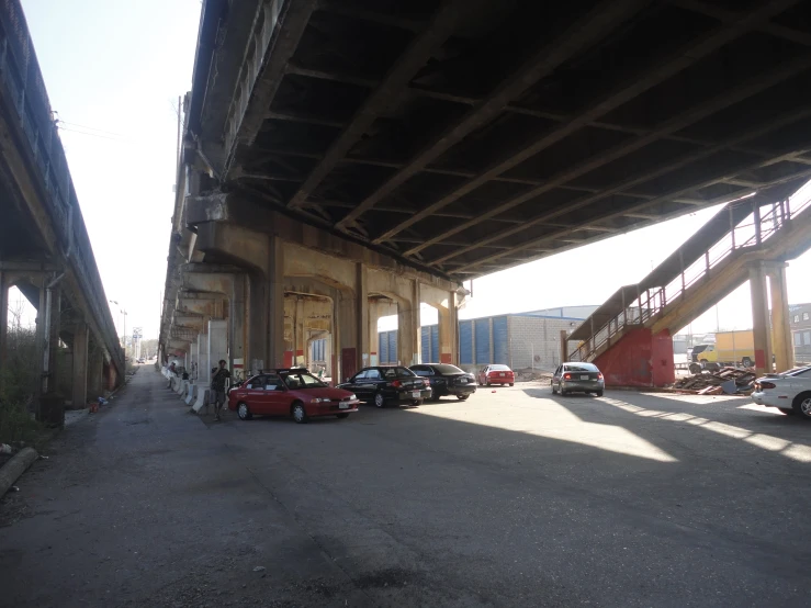 cars are parked beneath an overpass near a building