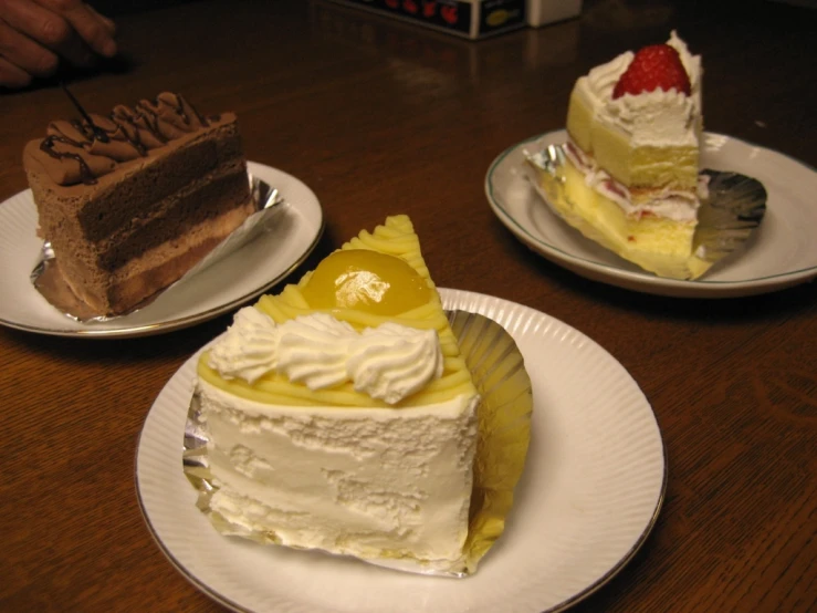 three pieces of cake are on white plates