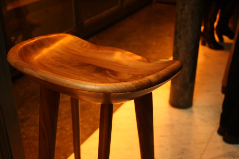 a wooden stool with a wooden seat in a room