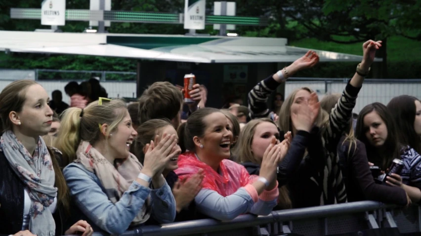 several women waving from behind the barriers