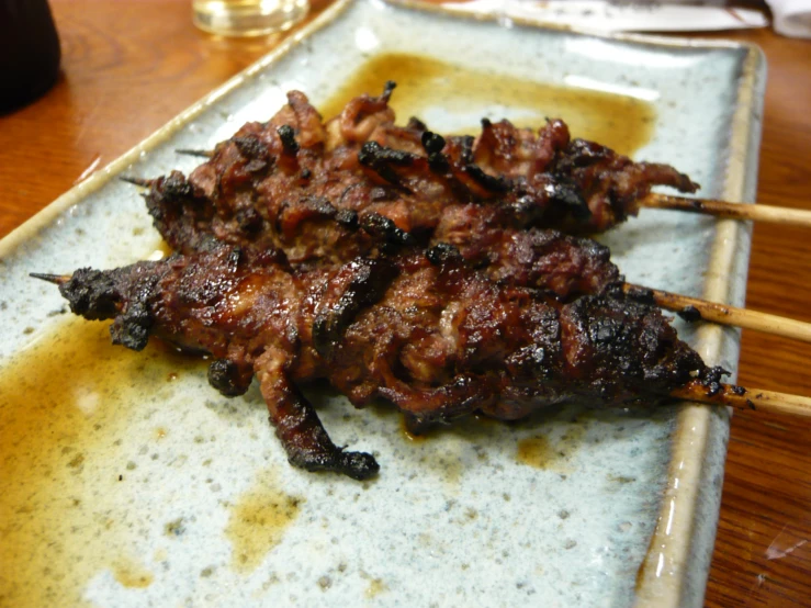 a close up of meat on sticks with mustard sauce