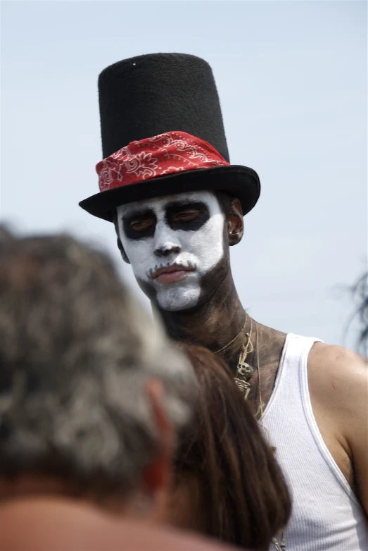 man with face paint at outdoor event in black hat and top hat