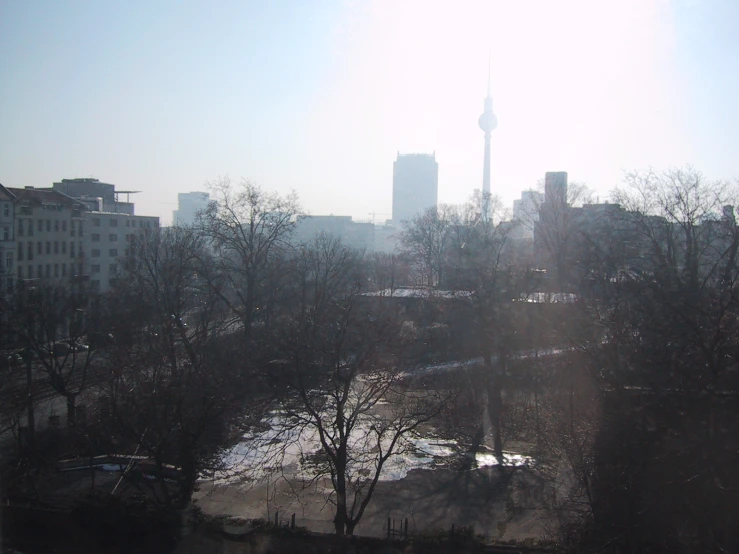 an out of focus picture of trees in a city with a tower in the distance