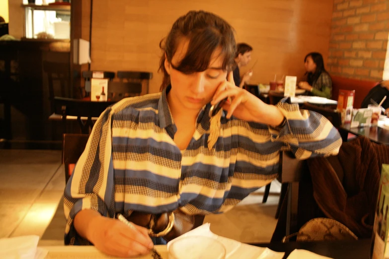 the girl is working at the table while on the phone