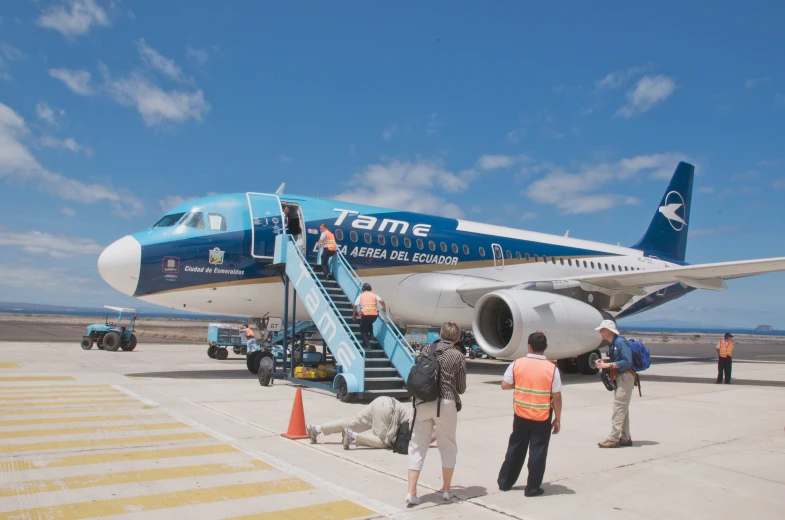 blue and white jet parked with four men preparing to board