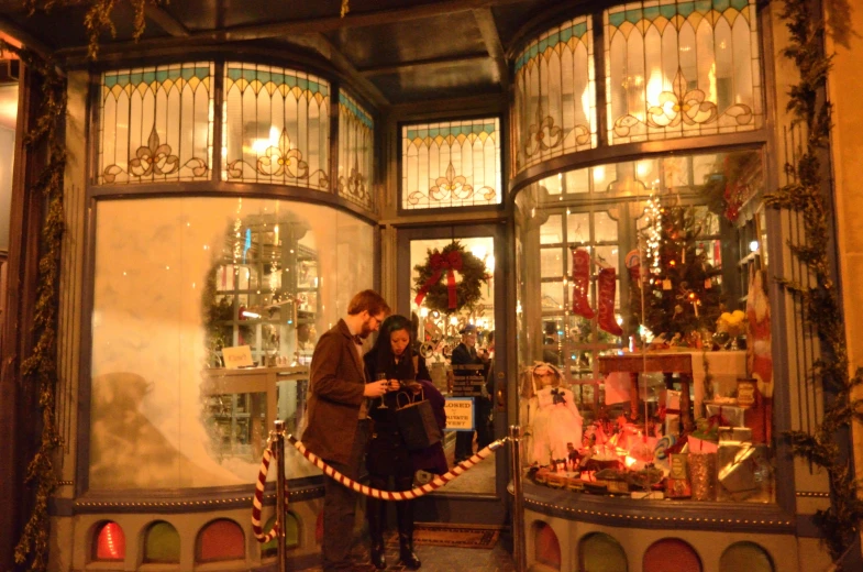 a couple looking at their cell phones in front of a christmas display