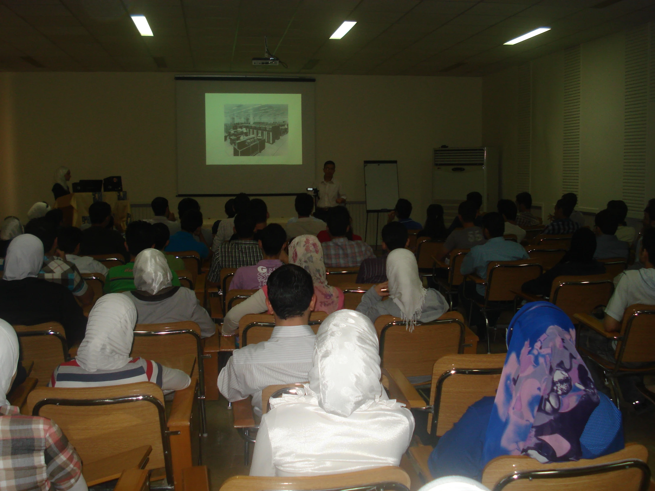 a classroom full of students watching a lecture on a screen