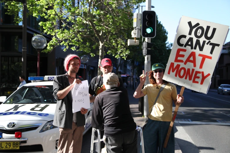 four men holding signs that say you can't eat money