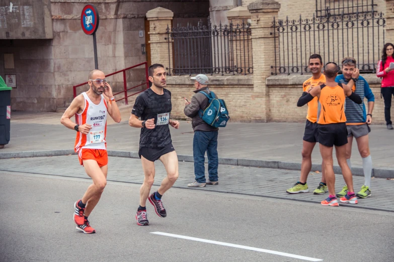 a man with  and shorts is running through the streets with people watching