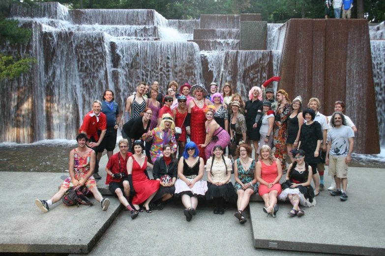 a group of people pose for a picture at the side of a waterfall