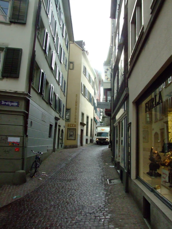 a narrow city street in a town with parked cars