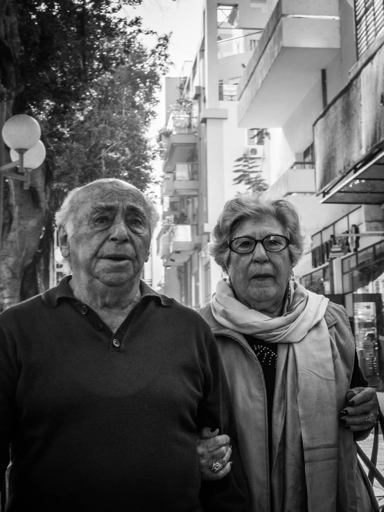 two older people standing in front of buildings