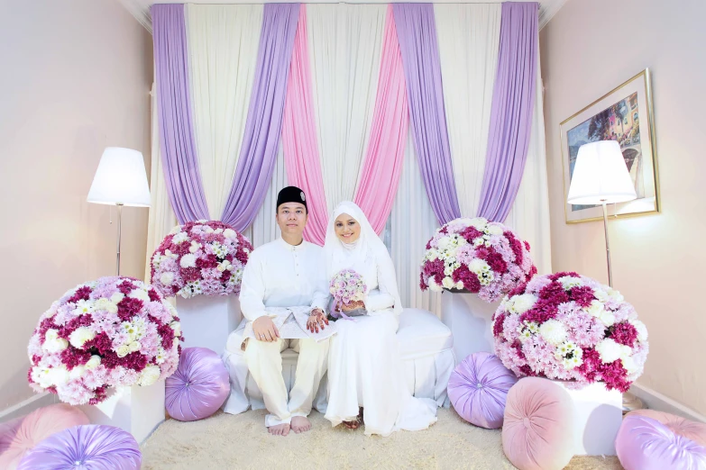 two people sitting on couch with many flowers in front of them