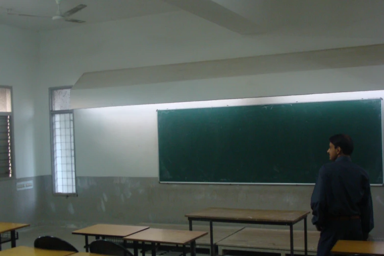 a boy standing in front of a blackboard in a classroom