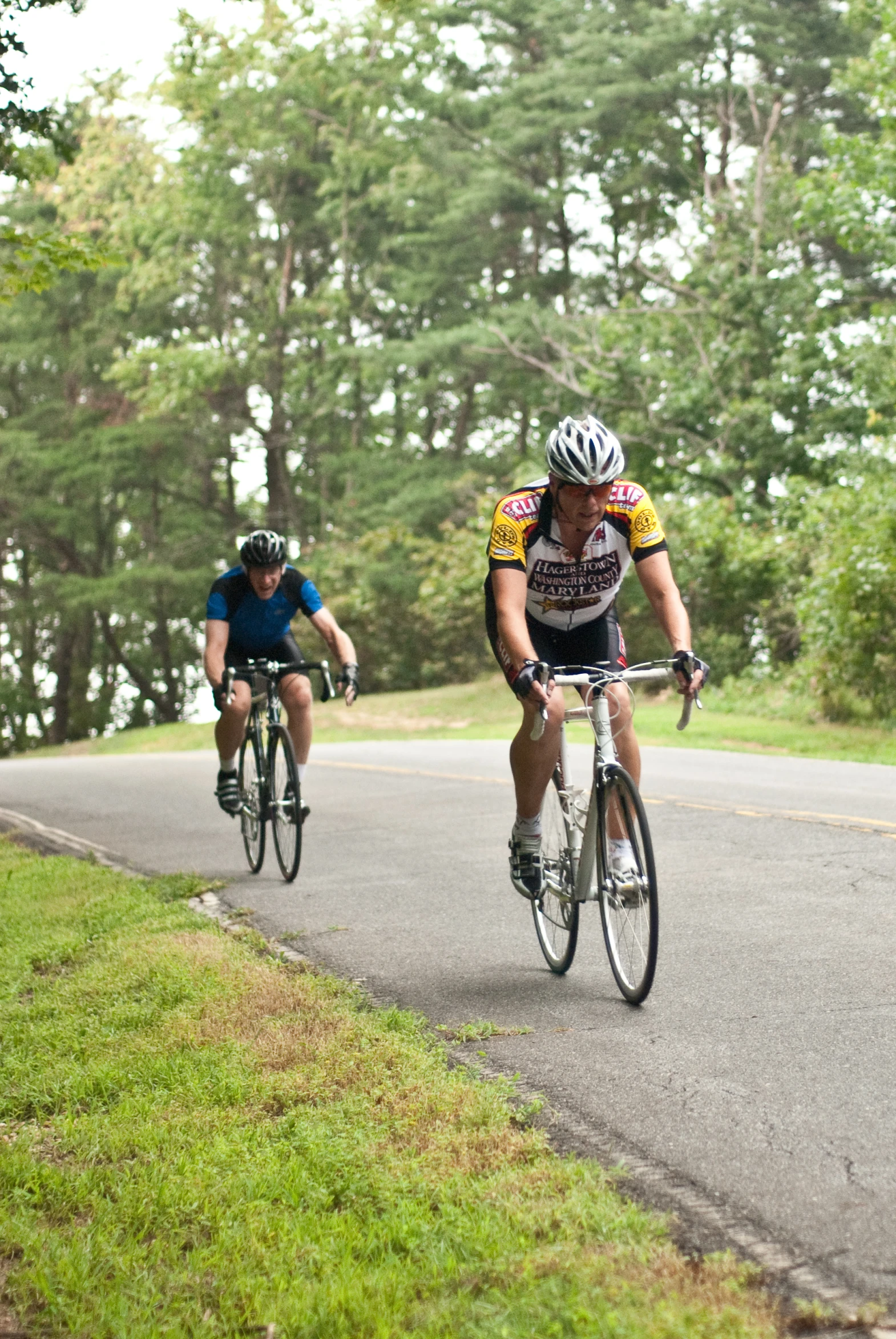 two men riding bicycles down a paved road