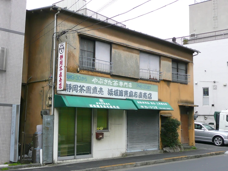 an old building with chinese writing and a green awning on a city street