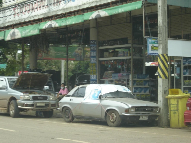 two older vehicles and one newer are sitting on the street