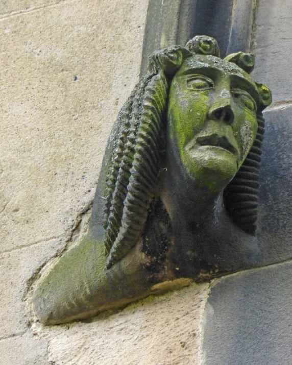 the head of a statue next to the door is covered with moss