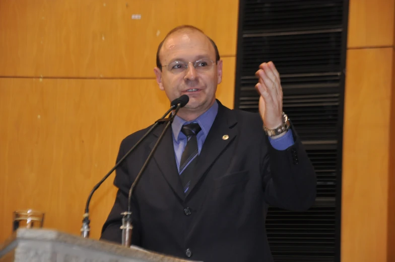 a bald man in a suit giving a speech