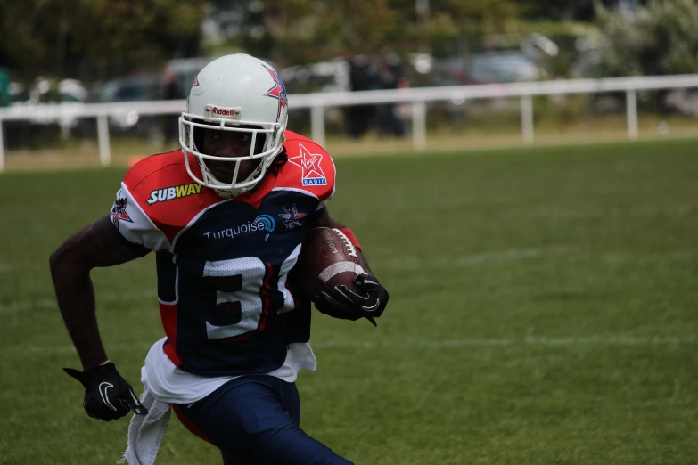 a football player carries a ball and runs