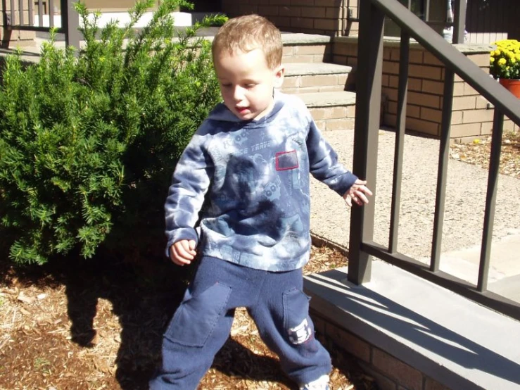 the little boy is standing on the porch outside