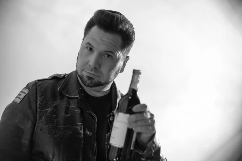 a man wearing a leather jacket holding a wine bottle