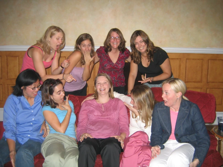 six women are sitting on a red couch posing for a po