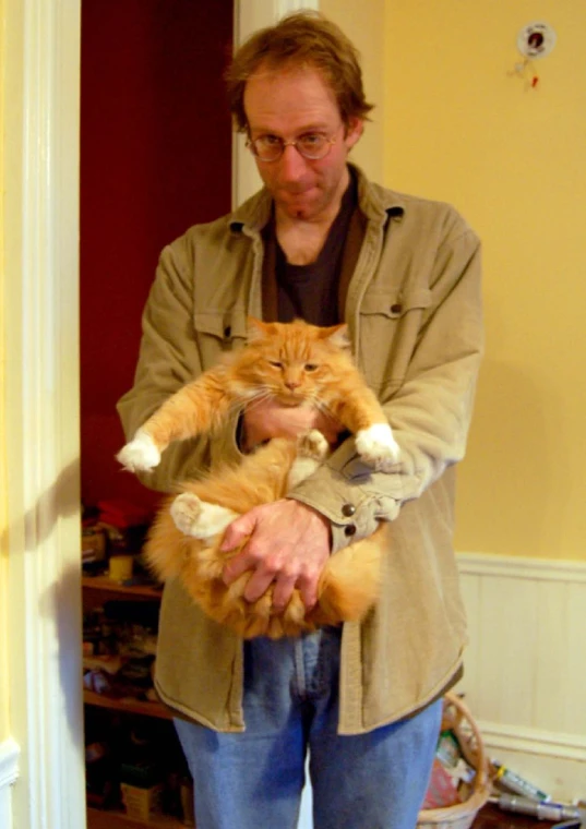 a man holds a cat up while he is holding it