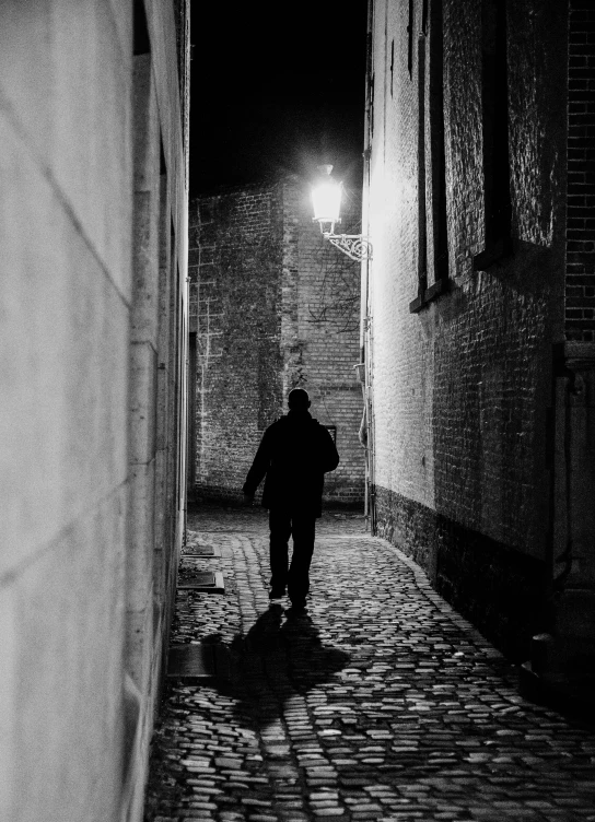 black and white pograph of a man walking down an alley way