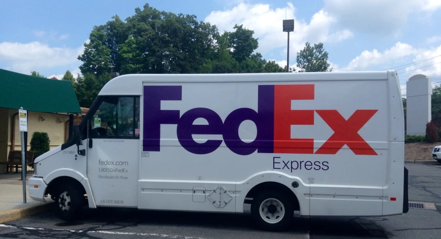 a fed ex truck parked on a road next to a parking lot