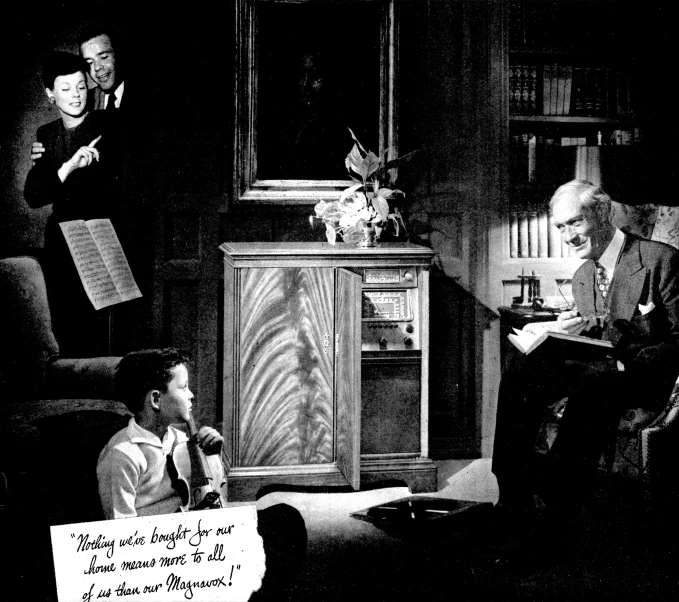 a black and white image of people at a living room table with a sign in front of them