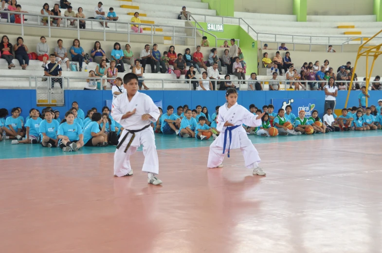two young men in white karate uniforms are in a match