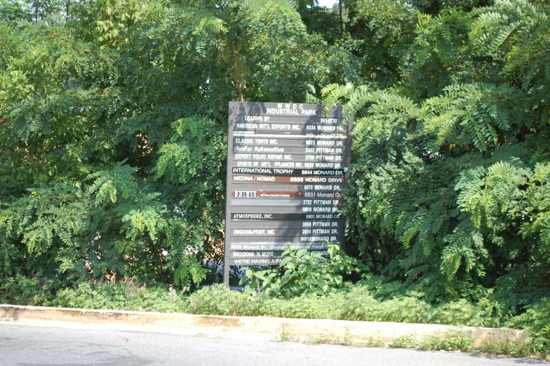 a sign sitting next to some trees on the side of a road