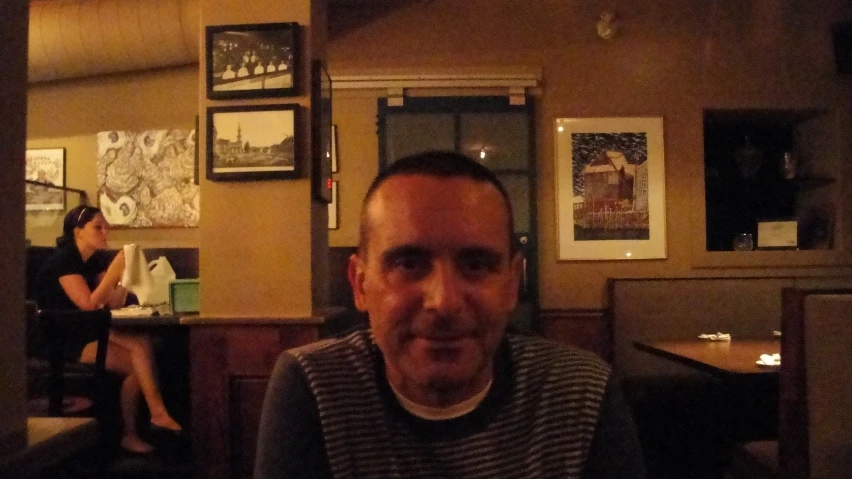 an older man sits in a restaurant, surrounded by tables and booths