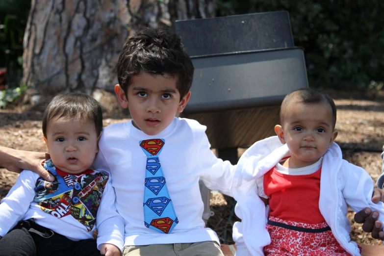 two small boys with ties sitting next to a woman