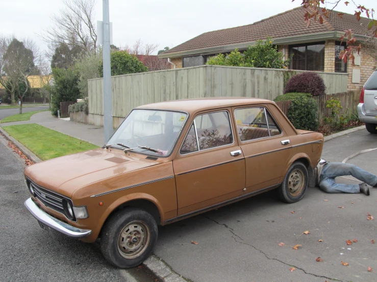 an old car parked in a driveway next to a young man